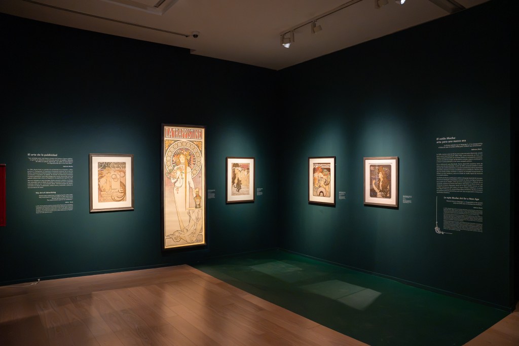 Sala de exposición de arte con varias obras enmarcadas y texto informativo en las paredes.